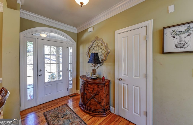 entryway with crown molding and wood finished floors