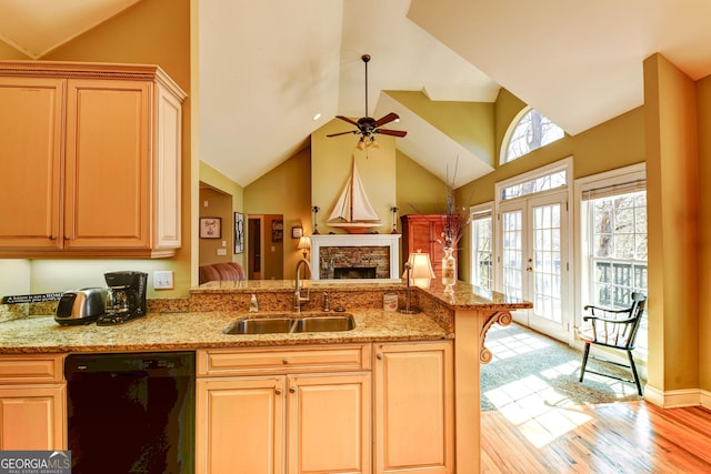 kitchen featuring dishwasher, a sink, a ceiling fan, a fireplace, and a peninsula