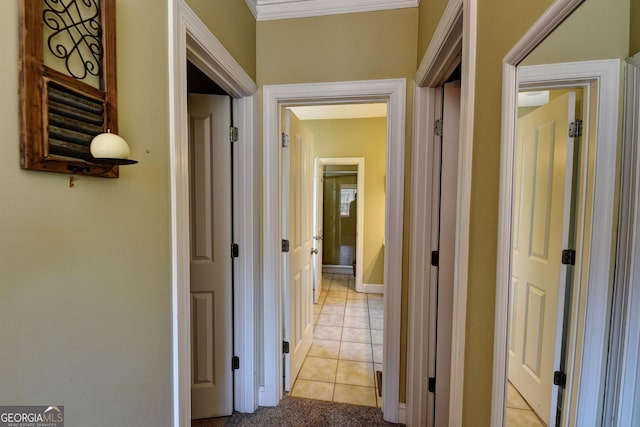 hall with light tile patterned floors, baseboards, and crown molding