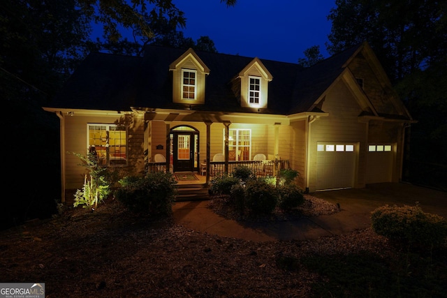 new england style home featuring covered porch, driveway, and a garage