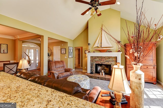 living area featuring high vaulted ceiling, a stone fireplace, light colored carpet, a ceiling fan, and crown molding