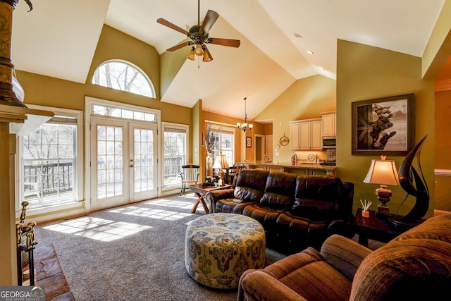 living area with light colored carpet, a ceiling fan, high vaulted ceiling, french doors, and a chandelier