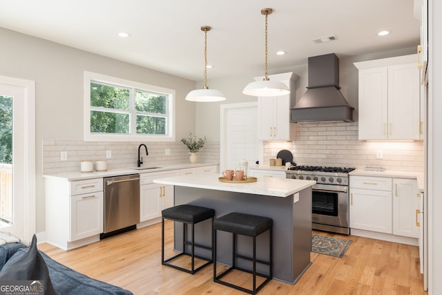 kitchen with premium range hood, a sink, white cabinetry, appliances with stainless steel finishes, and light countertops