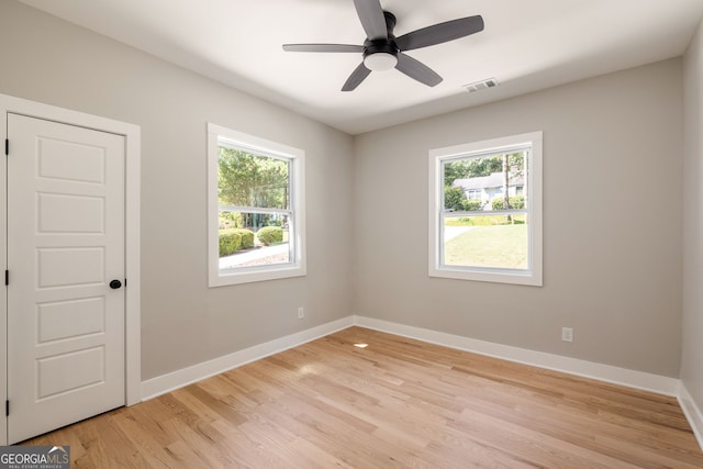 unfurnished room with a wealth of natural light, visible vents, light wood-style flooring, and baseboards