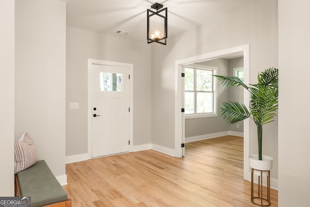 entryway featuring visible vents, baseboards, a notable chandelier, and light wood finished floors