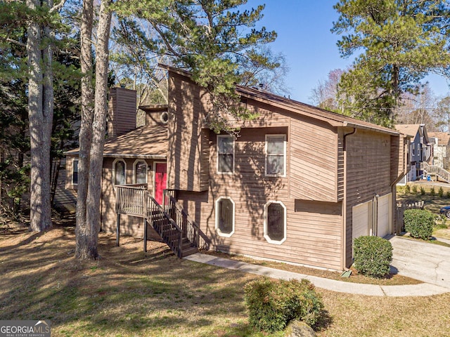 view of front of home with a front lawn, driveway, an attached garage, and stairs