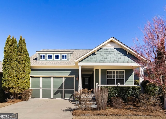 craftsman inspired home with an attached garage, a porch, concrete driveway, and roof with shingles