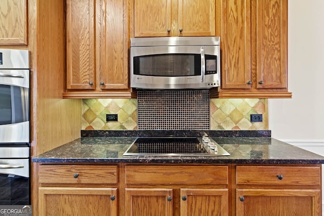 kitchen featuring stainless steel appliances, dark stone counters, and decorative backsplash