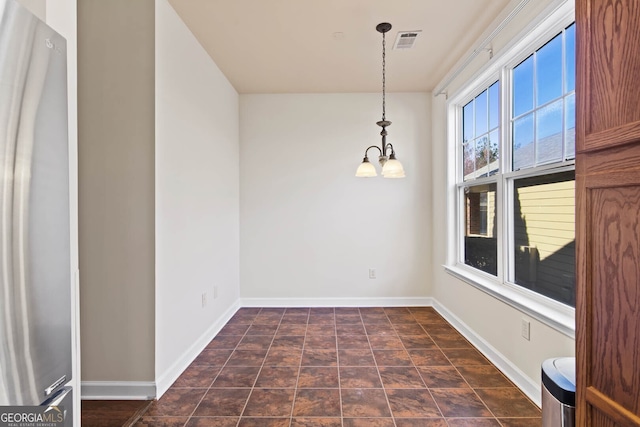 unfurnished room with visible vents, baseboards, and an inviting chandelier