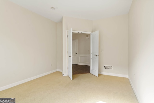 unfurnished bedroom featuring baseboards, visible vents, and light colored carpet