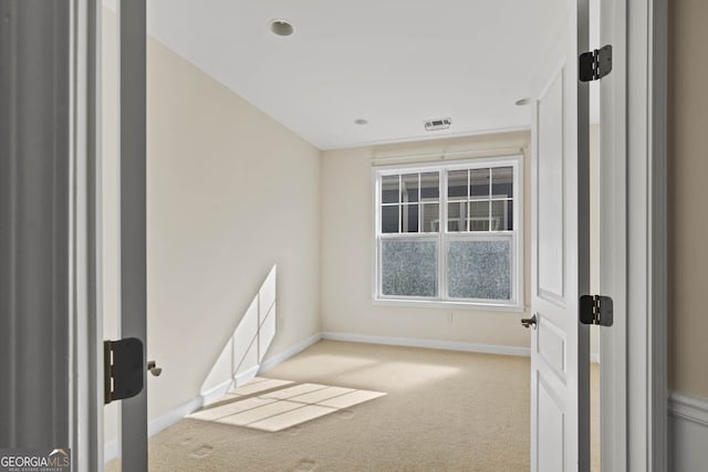 empty room with carpet, visible vents, and baseboards