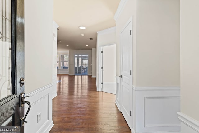 corridor featuring recessed lighting, a wainscoted wall, a decorative wall, wood finished floors, and crown molding