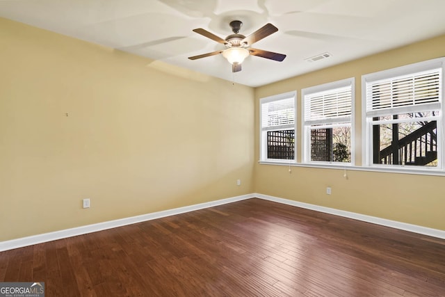 spare room with ceiling fan, wood finished floors, visible vents, and baseboards