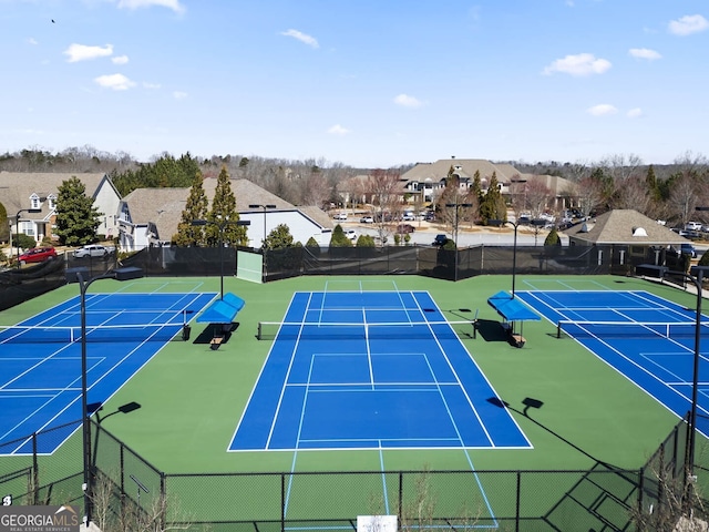 view of tennis court with a residential view and fence