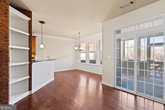 unfurnished dining area featuring dark wood-type flooring, a chandelier, visible vents, and crown molding