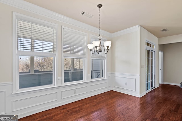 unfurnished dining area featuring a chandelier, wainscoting, visible vents, and hardwood / wood-style flooring