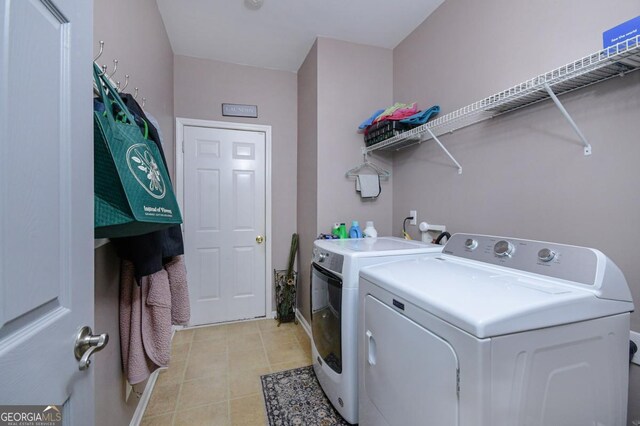 clothes washing area featuring laundry area, light tile patterned floors, and washer and dryer