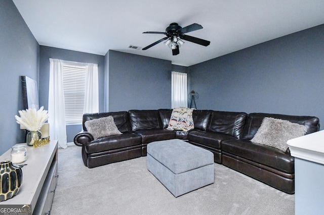 living room with baseboards, carpet, visible vents, and a ceiling fan