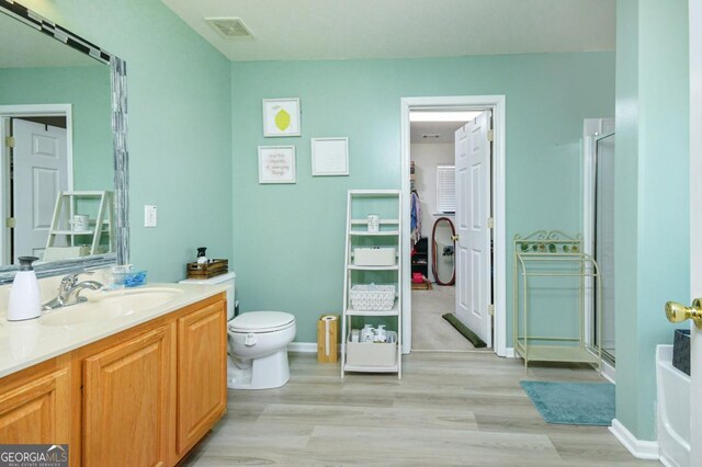 full bath featuring a stall shower, visible vents, vanity, and wood finished floors