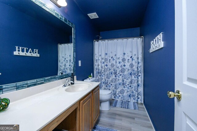 full bath with wood finished floors, vanity, toilet, and curtained shower