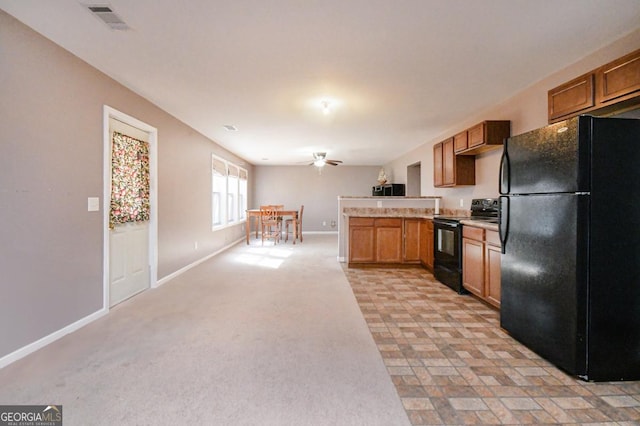 kitchen featuring a peninsula, visible vents, light countertops, brown cabinets, and black appliances