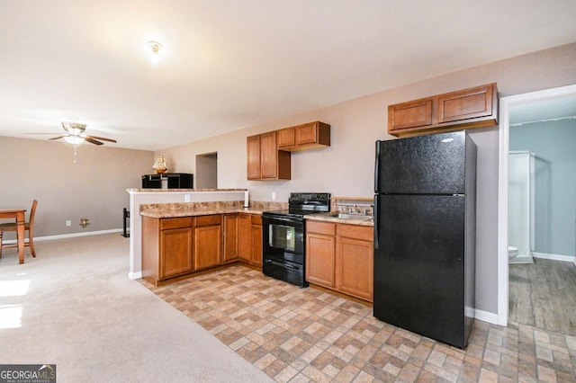 kitchen featuring brown cabinetry, ceiling fan, black appliances, a peninsula, and baseboards