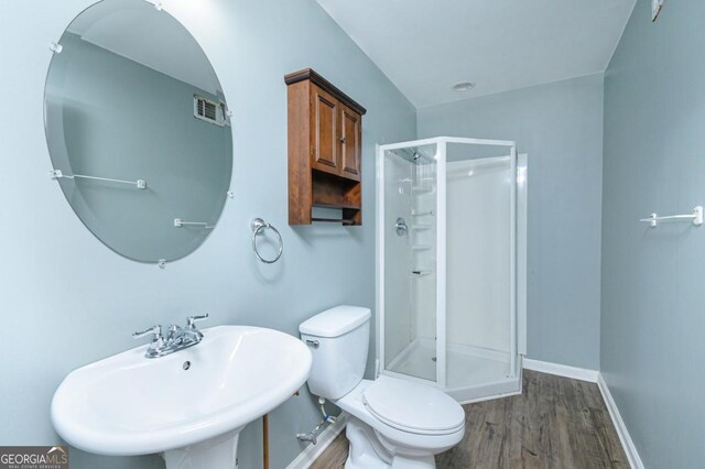 bathroom featuring toilet, wood finished floors, visible vents, a sink, and a shower stall