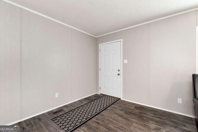 foyer entrance with a textured ceiling, ornamental molding, wood finished floors, and baseboards