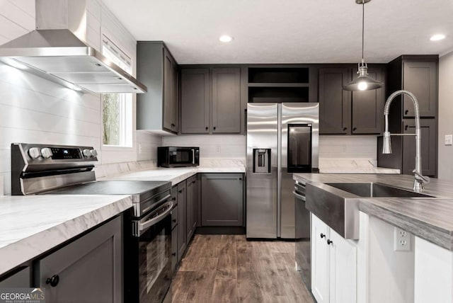 kitchen featuring stainless steel appliances, wall chimney exhaust hood, wood finished floors, and backsplash