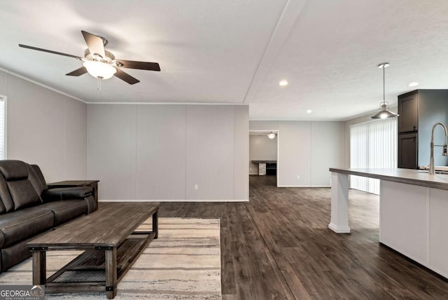 living area featuring dark wood-style floors, ceiling fan, a decorative wall, and recessed lighting