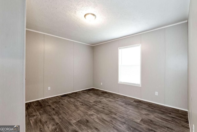 empty room with crown molding, a textured ceiling, and wood finished floors