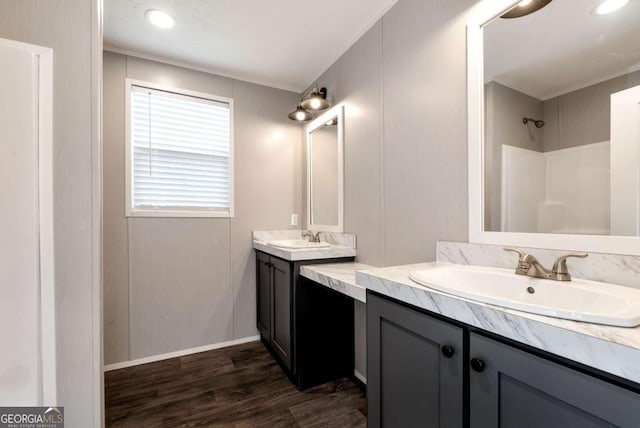 full bathroom featuring walk in shower, two vanities, a sink, and wood finished floors