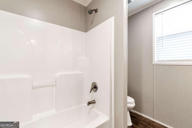 full bath with washtub / shower combination, wood finished floors, and toilet