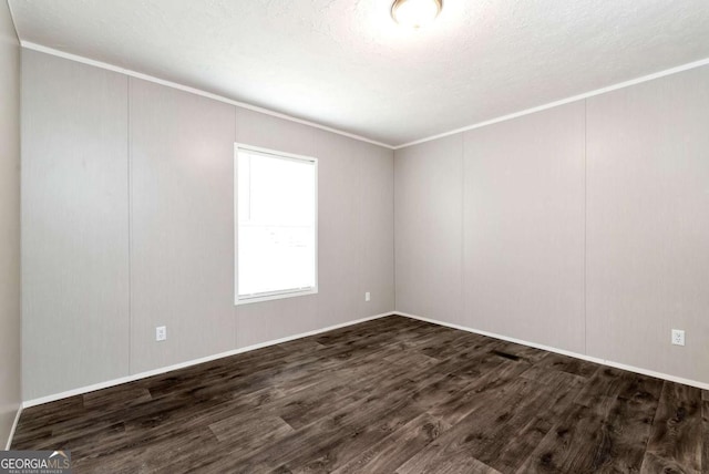 unfurnished room featuring dark wood-style floors, ornamental molding, and a decorative wall