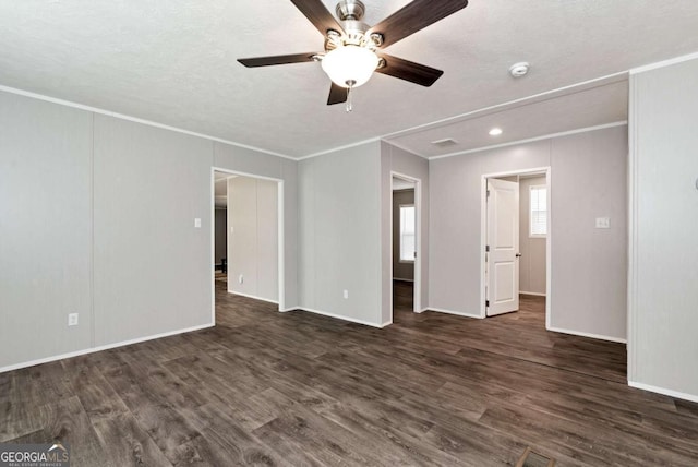 unfurnished bedroom featuring dark wood-style floors, ornamental molding, a textured ceiling, and baseboards