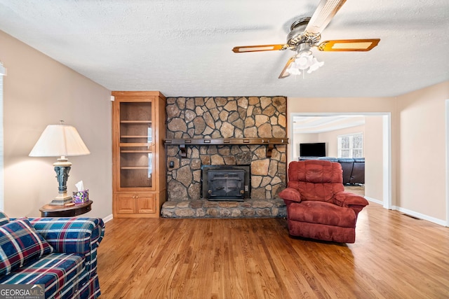 living room with a textured ceiling, baseboards, and wood finished floors