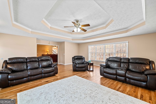 living area featuring a tray ceiling, a textured ceiling, wood finished floors, and crown molding