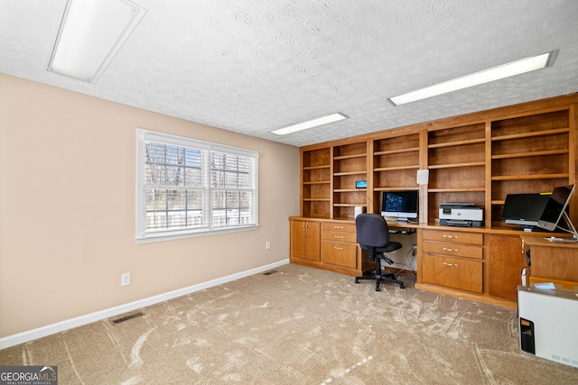 unfurnished office with visible vents, light colored carpet, a textured ceiling, and baseboards