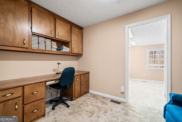 office space with baseboards, light colored carpet, visible vents, and a textured ceiling