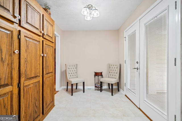 living area with light tile patterned flooring, baseboards, and a textured ceiling