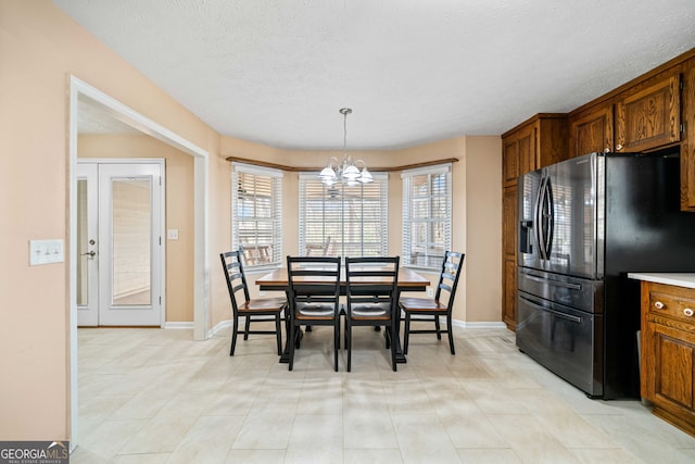 dining area featuring a notable chandelier, baseboards, and a textured ceiling