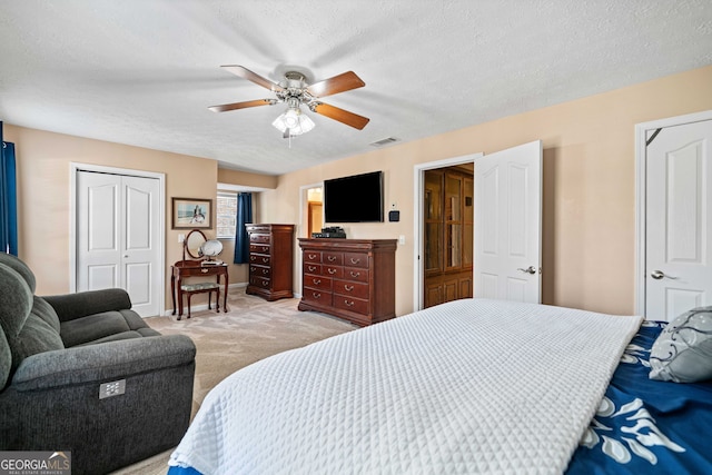 bedroom with visible vents, light carpet, a textured ceiling, and a closet