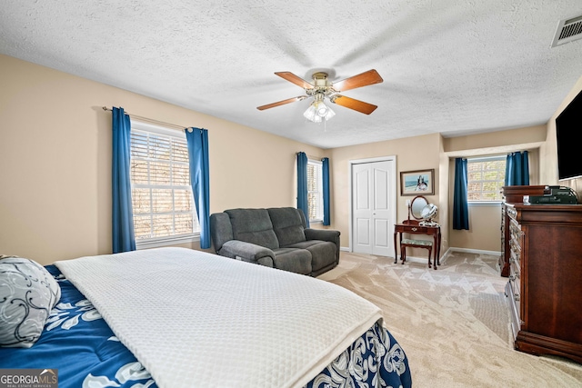 bedroom featuring visible vents, baseboards, light carpet, a closet, and a ceiling fan