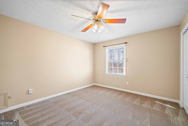 carpeted empty room featuring baseboards, a textured ceiling, and ceiling fan