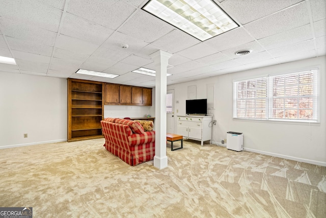 living area with a drop ceiling, visible vents, baseboards, and light colored carpet