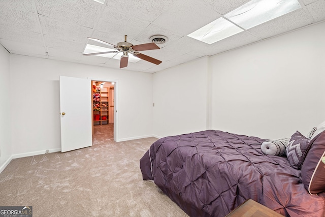 carpeted bedroom with a paneled ceiling, visible vents, baseboards, and ceiling fan