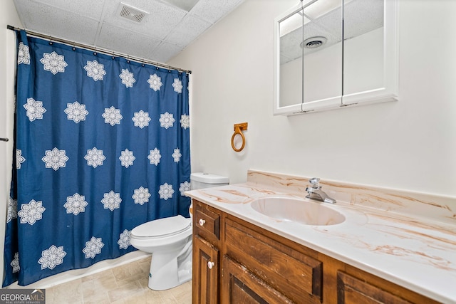 bathroom featuring visible vents, a paneled ceiling, toilet, and vanity