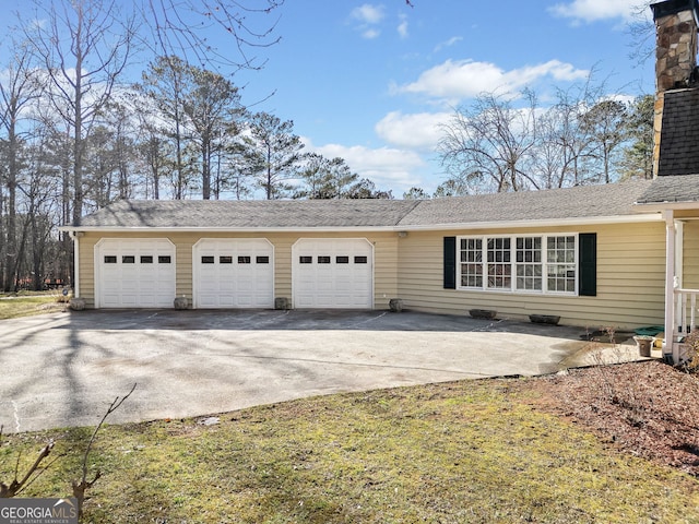 exterior space featuring an attached garage, driveway, and a chimney