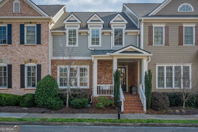 townhome / multi-family property featuring brick siding and a porch
