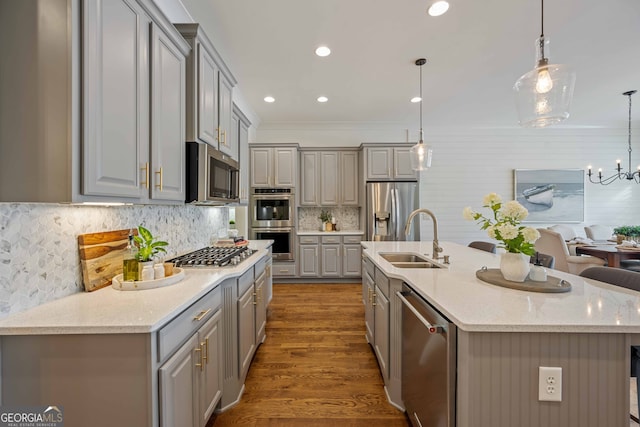 kitchen with appliances with stainless steel finishes, a sink, gray cabinetry, and wood finished floors